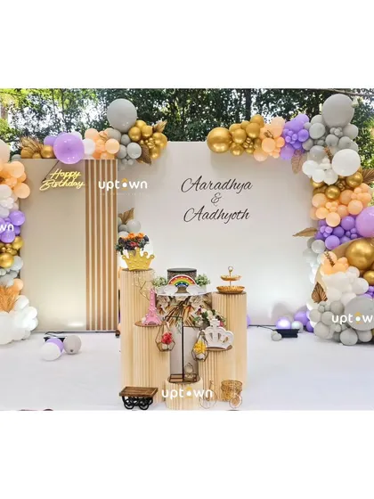 An elegant outdoor setup for a twins' birthday party with pastel and gold balloons.