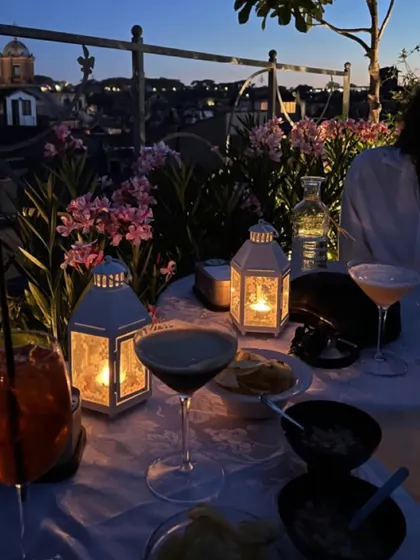 An evening of cocktails and conversation on a rooftop. This setup for a private dinner includes expertly crafted martinis and appetizers, with candle-lit lanterns creating a serene and romantic mood against the city skyline.