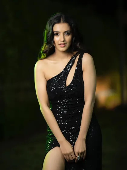 A sleek and sexy black sequined gown. The off-camera lighting with a green tint adds a touch of mystery and drama, perfect for a nighttime or event-themed shoot.