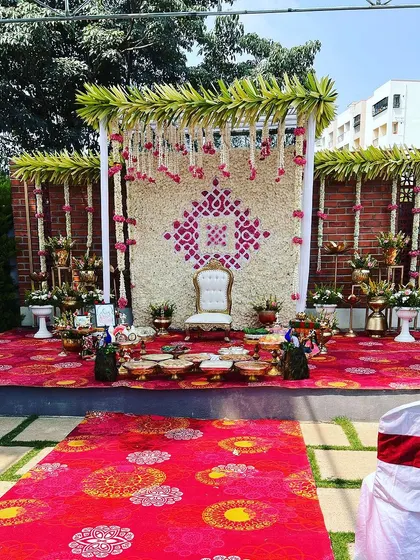 We also specialize in beautiful outdoor setups for traditional functions. This Seemantham (baby shower) ceremony features a floral wall of white and pink against a rustic brick background, complete with a traditional white chair for the mother-to-be.