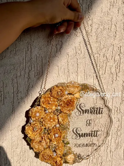 A beautiful wall hanging frame made from a preserved varmala. The golden roses and pearls create a stunning visual against the clear resin, making it a perfect wedding gift.