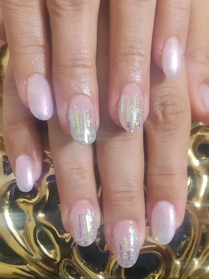 This set combines a soft, shimmery pink polish with accent nails that have vertical holographic foil strips for a modern, striped look.
