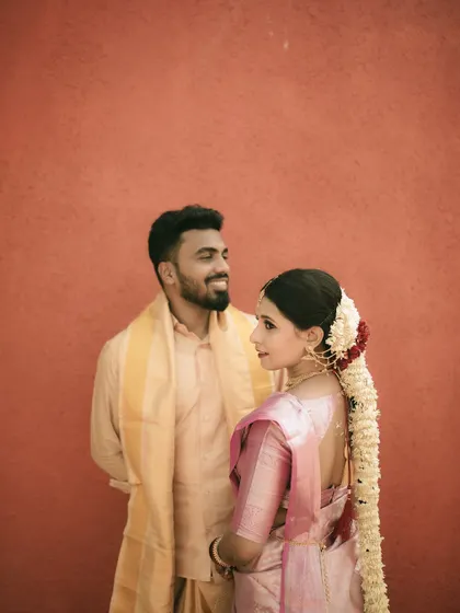 A beautifully composed portrait against a bold, red wall, highlighting the couple's traditional attire.