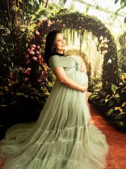 A side profile in a flowing green gown against the enchanted forest backdrop. The lighting creates a magical, storybook feel.