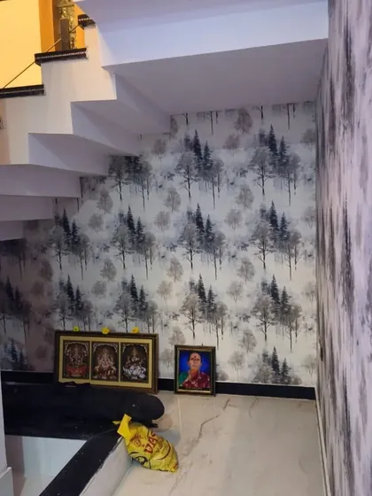 A subtle tree pattern wallpaper adds texture and interest to the often-overlooked space under a staircase. This monochrome design creates a sense of depth and brings a calming, natural element to the home's interior.