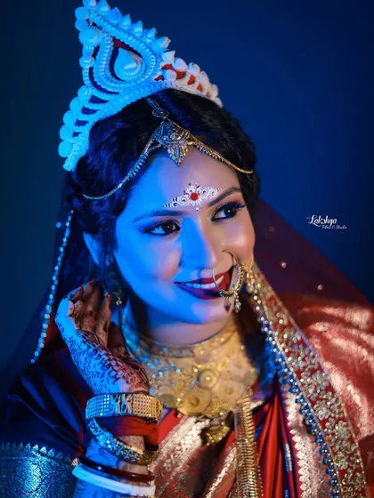 A beautiful portrait of the Bengali bride under dramatic blue light. Her expression is full of grace and happiness, capturing her bridal glow perfectly.