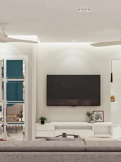 This view showcases a bright, all-white living room where a discreetly designed pooja unit is integrated into the wall cabinetry. The use of mirrored panels on the adjacent storage unit helps to reflect light and make the space feel larger.