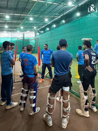 A team briefing in the nets. The coach discusses tactics and gives instructions to a group of attentive players before a drill.
