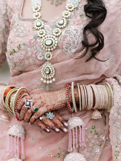 A detailed shot of the bride's hands, adorned with henna and bangles, showcasing her stunning polki jewelry.