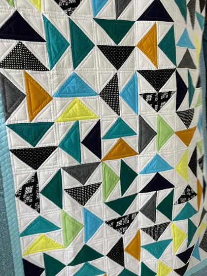 A close-up of the "Twisted Geese" quilt, showing the mix of solid and patterned fabrics.