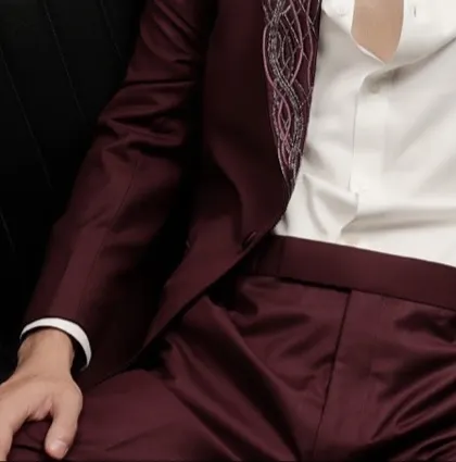A detail shot of the burgundy tuxedo's fabric and the delicate embroidery on the lapel. The rich color and texture make it a standout piece.