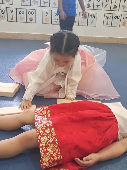 Two children work together to measure one another with blocks, demonstrating teamwork and peer learning.