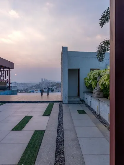 The terrace landscaping uses a mix of stone pavers, pebbles, and synthetic grass strips to create a clean, geometric pattern. This low-maintenance approach is perfect for a modern rooftop environment.