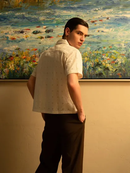 A colorful and artistic portrait for a male model. The warm lighting and the painting in the background create a rich, creative atmosphere.