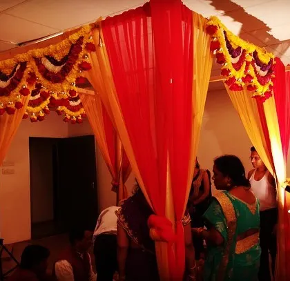 I design for weddings of all sizes, including intimate home ceremonies. This simple yet elegant mandapam is built with vibrant red and yellow drapes and marigold garlands, perfect for a traditional home wedding.