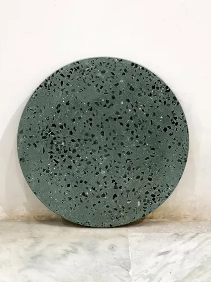 A full view of the round olive green terrazzo tabletop. This versatile piece can be used to create a custom side table or coffee table with a unique, modern feel.