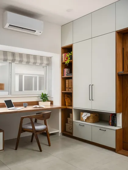 A view of the 'Palaash' home office with the Murphy bed folded up. The space is clean and organized, with a combination of open and closed storage.