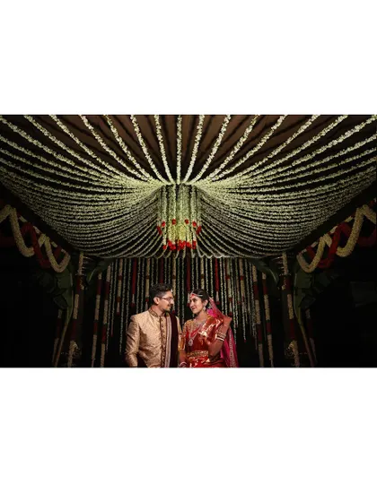 A wide shot of the couple in their beautifully decorated wedding mandap, capturing the grandeur of the setting.