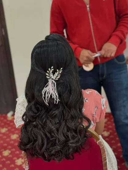 A behind-the-scenes shot of the feather accessory being placed. It's these unique details that make a hairstyle truly special.