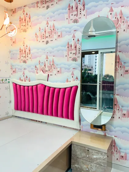 A glimpse into a princess-themed kids' bedroom I completed. The design features a vibrant pink upholstered headboard against a castle-themed wallpaper, a floating dressing table with an oval mirror, and coordinated furniture.