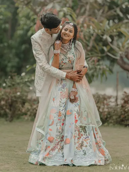 A playful and loving embrace in the garden. The groom's hug from behind and the bride's happy smile make this a heartwarming shot.