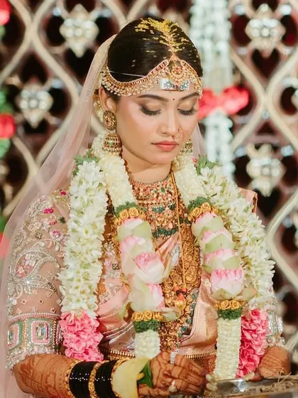 A close-up of the bride's beautiful smile and her stunning pastel ensemble. The intricate details of her jewelry and the embroidery on her blouse are simply breathtaking.