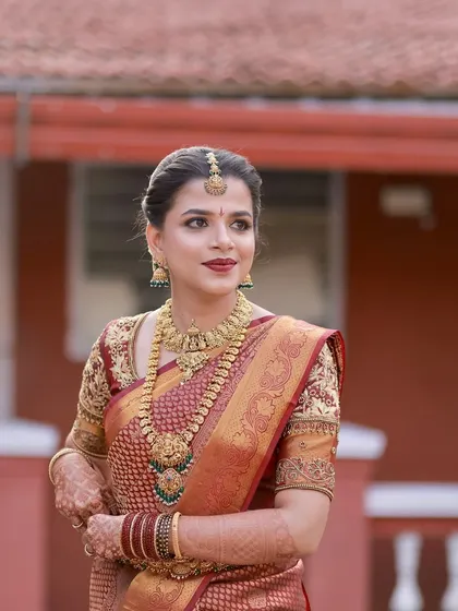 This bride looks regal in her maroon silk saree. Her makeup is classic and polished, with a red lip and perfectly defined brows.
