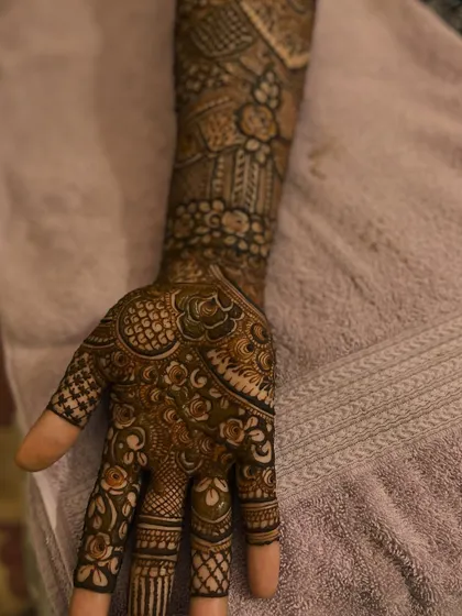 A close-up of the palm and fingers, showing the detailed patterns of the engagement henna.