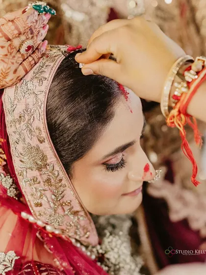 A close-up shot of the 'sindoor' ceremony, a deeply significant and emotional moment in a Hindu wedding.