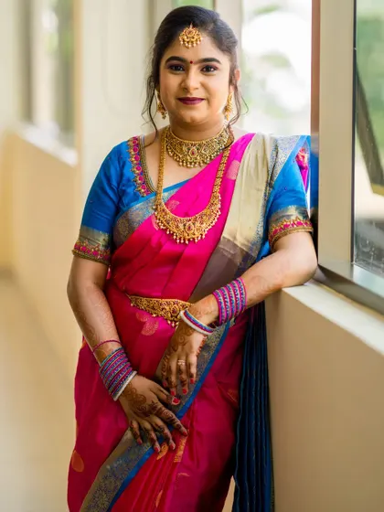 This bride is ready for her wedding ceremony in a vibrant pink and blue saree. I created a balanced look with defined eyes and a soft lip color to go with her traditional gold jewellery.