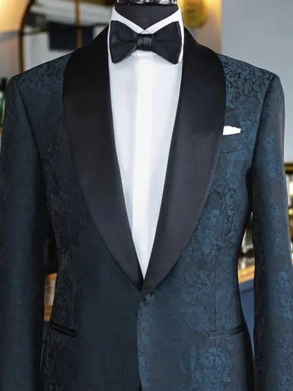 This dark, patterned tuxedo jacket offers a subtle twist on the classic. The jacquard fabric with a floral design is visible up close, giving it a very luxurious feel.