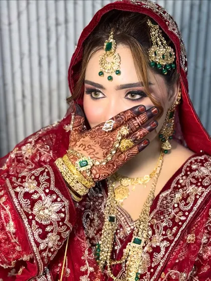 This is the same Nikkah bride, showcasing the complete look with her heavy jewelry and traditional red dupatta. The makeup was designed to be bold enough to balance the ornate details of her attire.