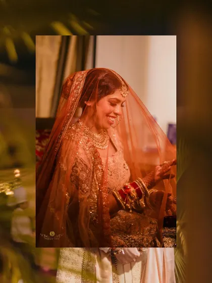 A beautiful, candid moment of the bride smiling under her veil. The warm, soft lighting creates an intimate and joyful atmosphere.