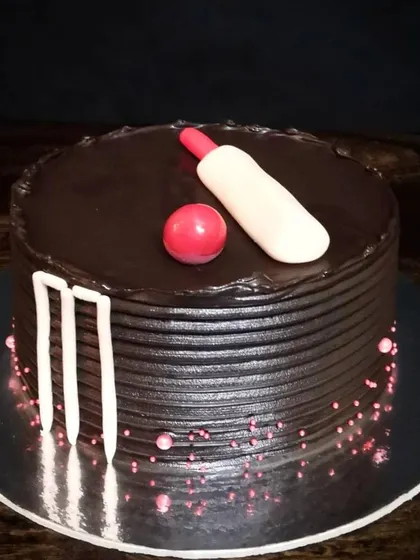 A minimalist cake for a cricket enthusiast. This chocolate cake is simply decorated with fondant wickets, a bat, and a ball, proving that you don't need a lot of decoration to make a big impact.