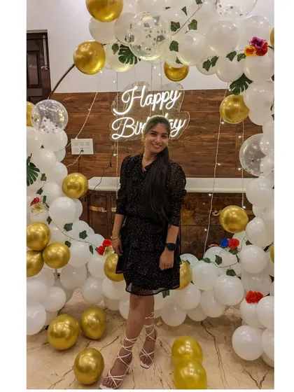 A happy client posing in front of her beautiful white and gold birthday decorations.