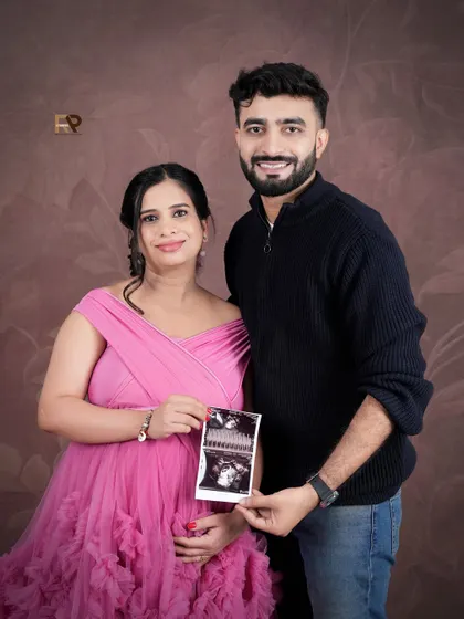 A beautiful couple's portrait featuring the ultrasound scan. The mom-to-be is glowing in a pink gown, her expression full of love and excitement.