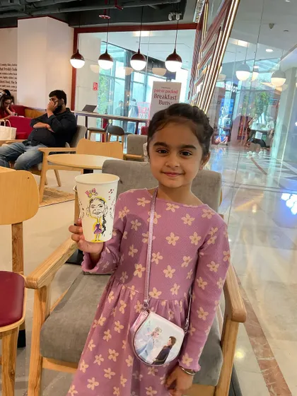 A cute little girl with her personalized caricature cup at Pret A Manger.