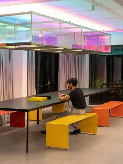 The Community Table at night, with the iridescent light fixture casting a colorful glow. This space reflects our belief that a workplace should have moments of fun and exuberance, balanced with an overall atmosphere of purpose and calm.