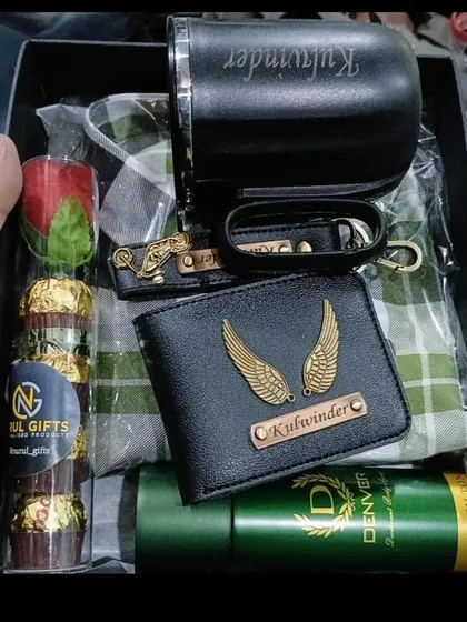 A detailed look at a packed gift hamper containing a personalized wallet, keychain, and mug, along with a shirt, deodorant, and chocolates.