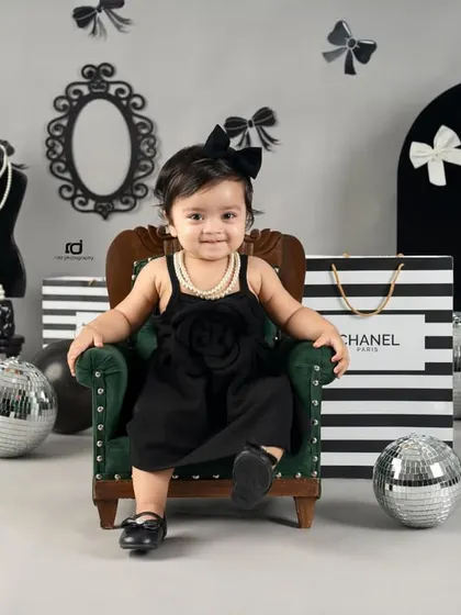 This little fashionista is sitting confidently in her mini armchair, surrounded by stylish props.