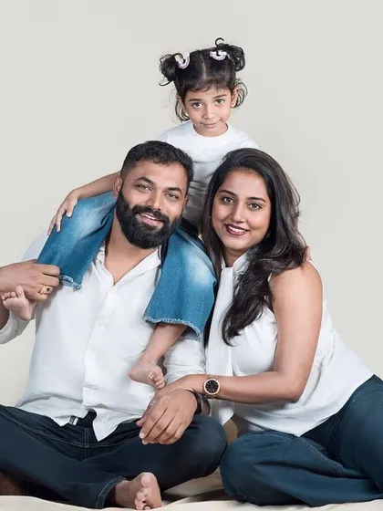 A classic family-of-three portrait. The daughter perched on her father's shoulders adds a playful touch to this happy and relaxed studio photo.