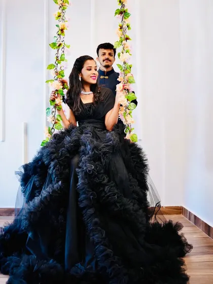 A glamorous pre-wedding shot featuring our black ruffled gown. The floral swing adds a touch of whimsy and romance to this elegant couple portrait.
