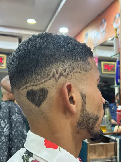 A creative combination of designs. This haircut features a heartbeat line leading into a solid heart shape, all carved into a clean fade with a sharp beard lineup.
