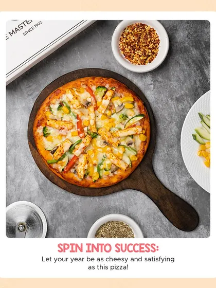 An overhead view of our fully loaded veggie and paneer pizza, surrounded by chili flakes and oregano. It's a cheesy and satisfying meal perfect for sharing.