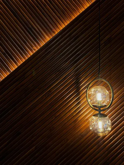 A detail shot capturing the beautiful interplay of light from a pendant fixture against the diagonally fluted wood paneling.