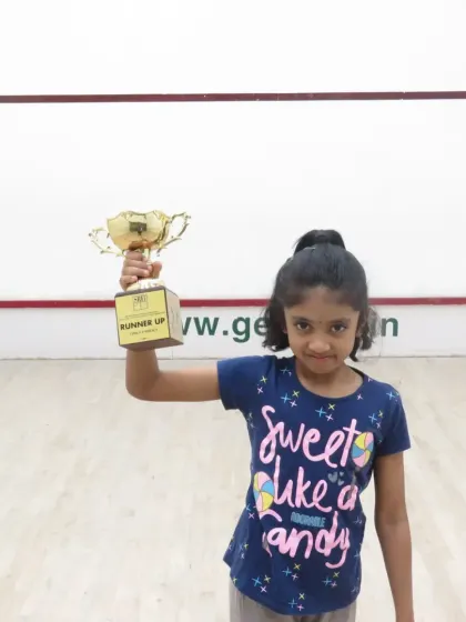 Tulasimira proudly holding her runner-up trophy. It's this kind of achievement that fuels our passion for coaching the next generation of squash players.