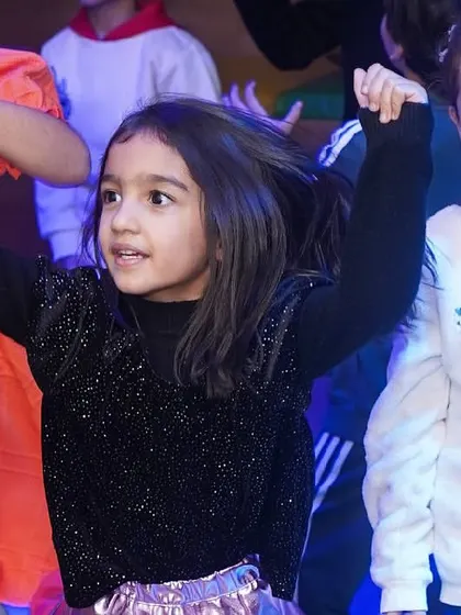A girl dances with her hands in the air, having the time of her life.