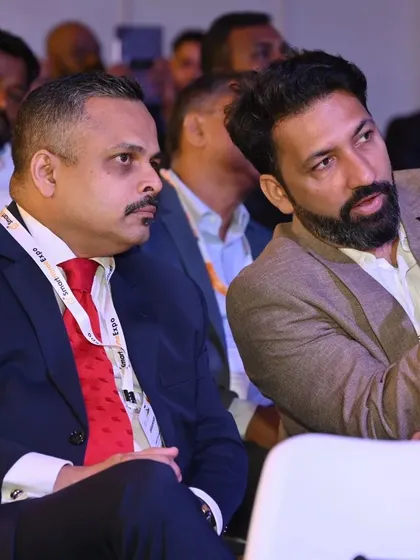 A focused discussion between two professionals during a conference, illustrating the opportunities for peer-to-peer knowledge sharing.