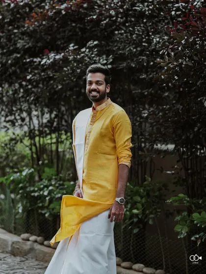 A handsome portrait of the groom in a yellow and white traditional outfit.