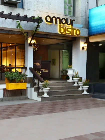 The facade of Amour Bistro in New Delhi creates a charming, European-inspired street presence. The design offers a tranquil, native ambiance amidst the city's chaos, inviting passersby into its warm and elegant interior.